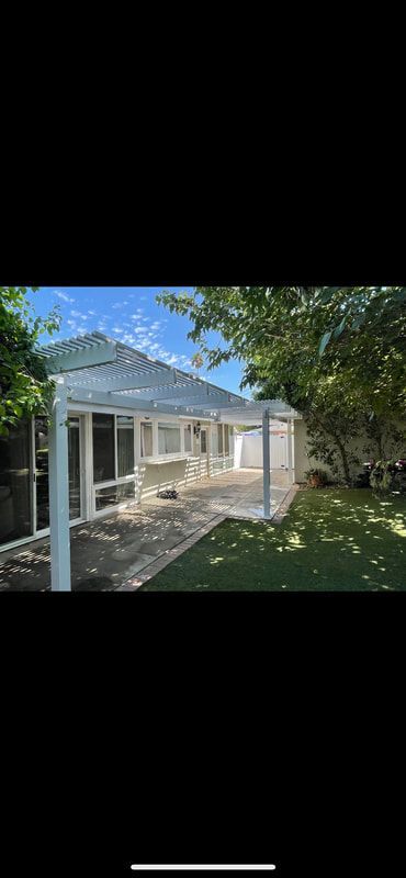 A white house with a large covered patio in the backyard.
