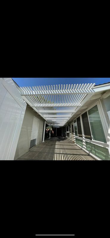 A white building with a covered walkway between two buildings.
