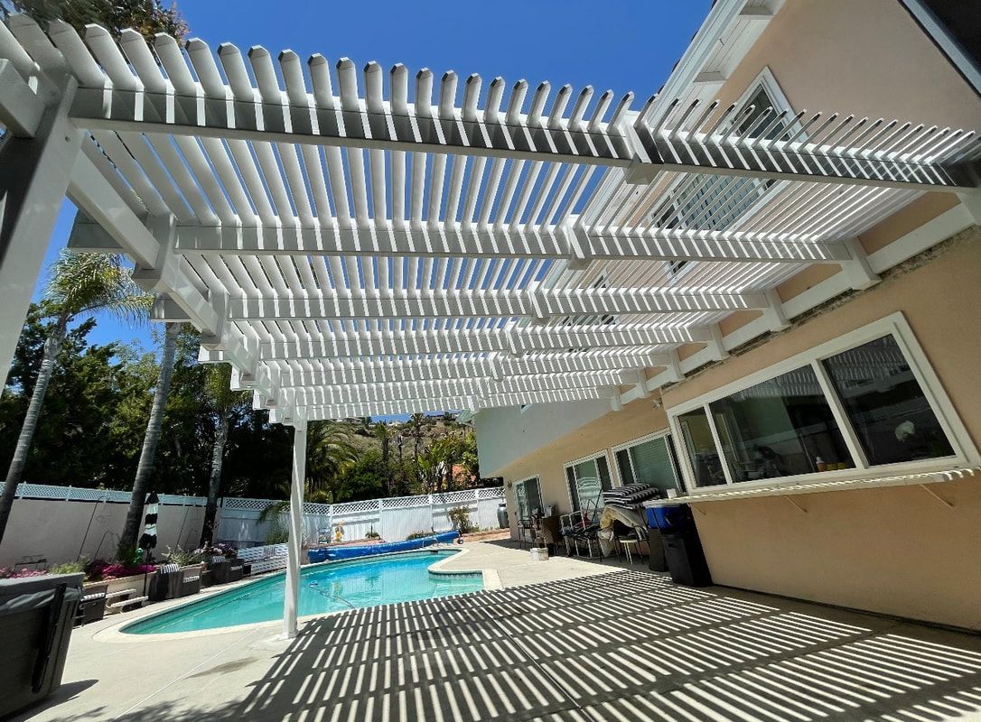 A white pergola over a swimming pool in a backyard.