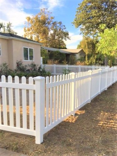 A white picket fence is in front of a house.
