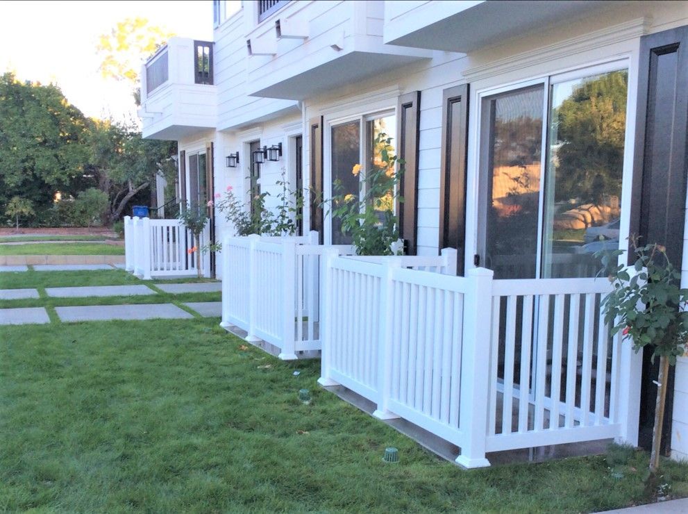 A row of white houses with a white fence in front of them.