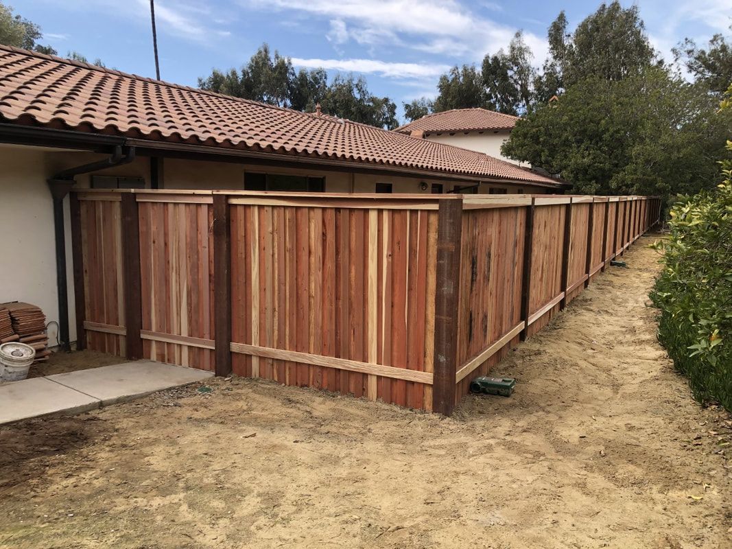 A wooden fence is sitting in front of a house.
