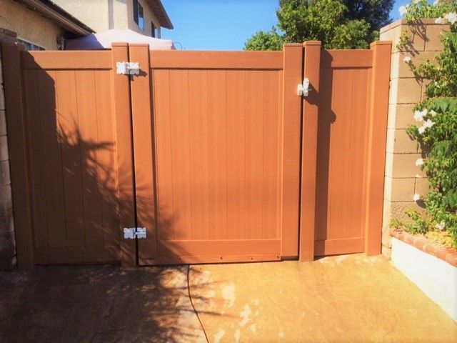 A wooden fence with a gate in front of a house.