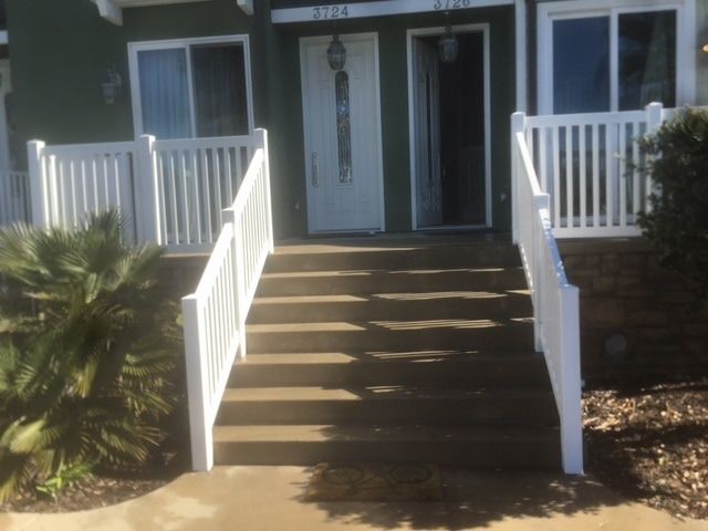 The front of a house with stairs and a white railing