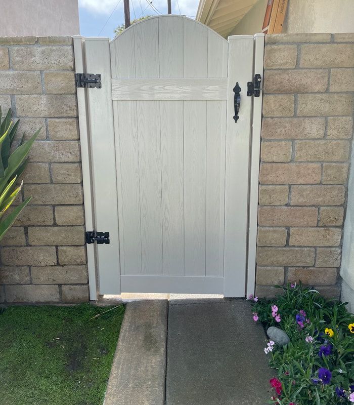A white gate is sitting in front of a brick wall.