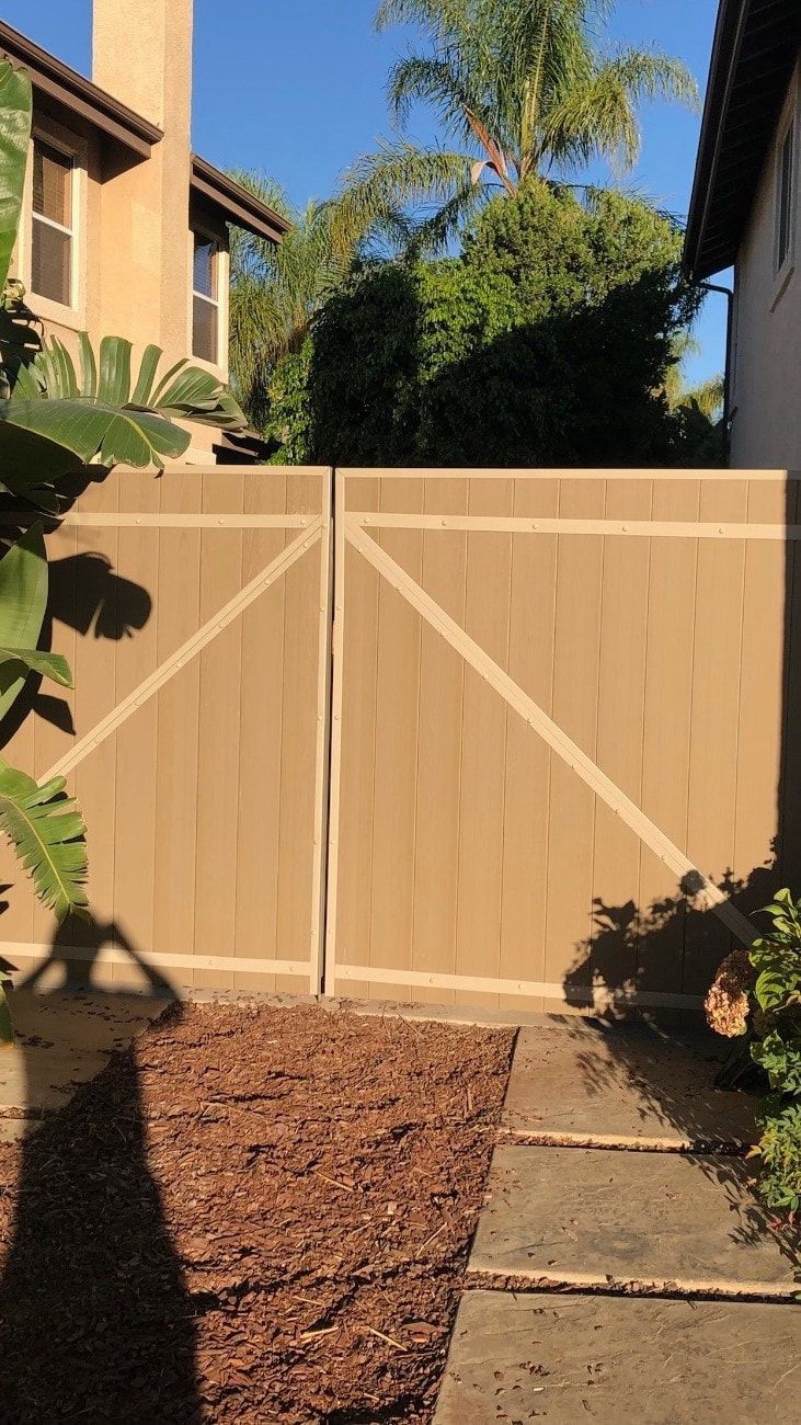 A wooden fence is in the backyard of a house.