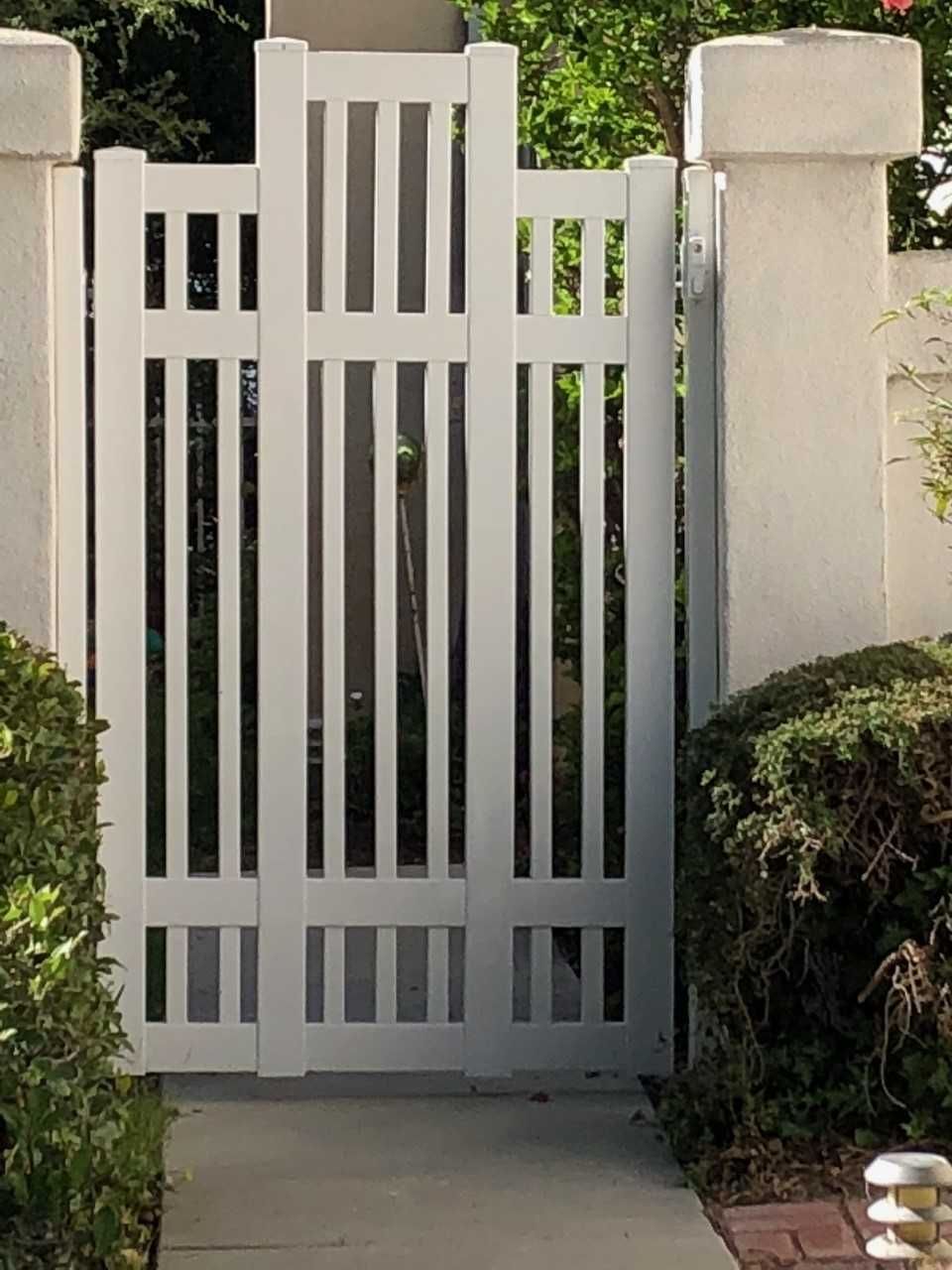 A white gate with a brick walkway behind it