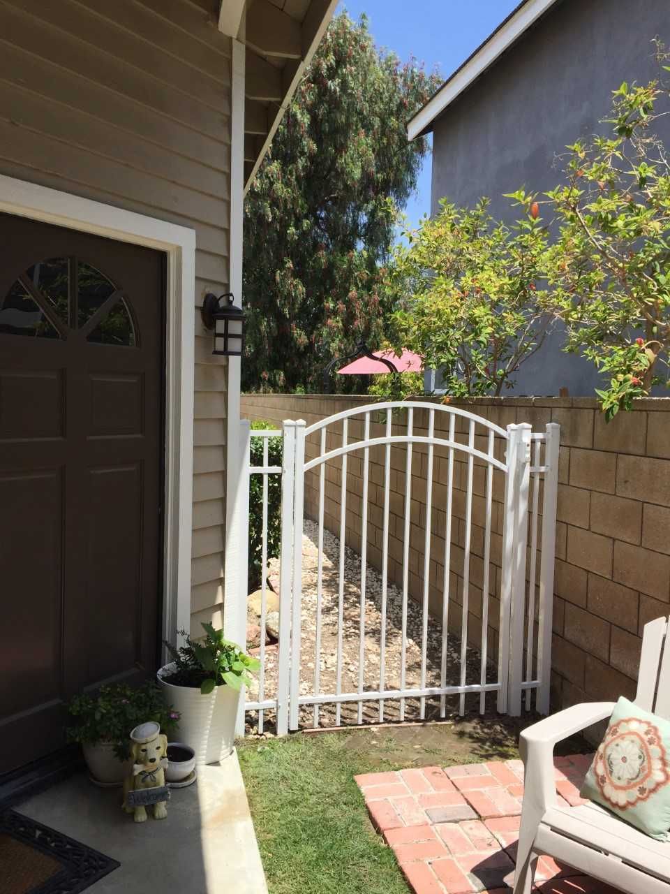 A white gate is in the backyard of a house