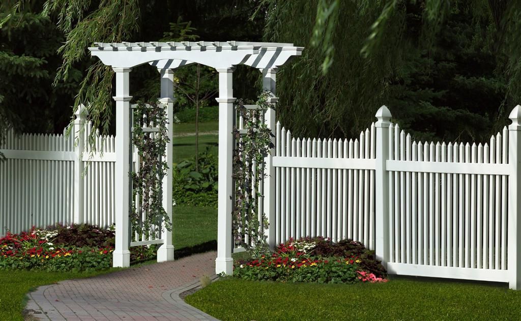 A white picket fence with a pergola in the backyard