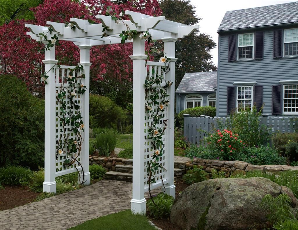 A white pergola is in front of a house