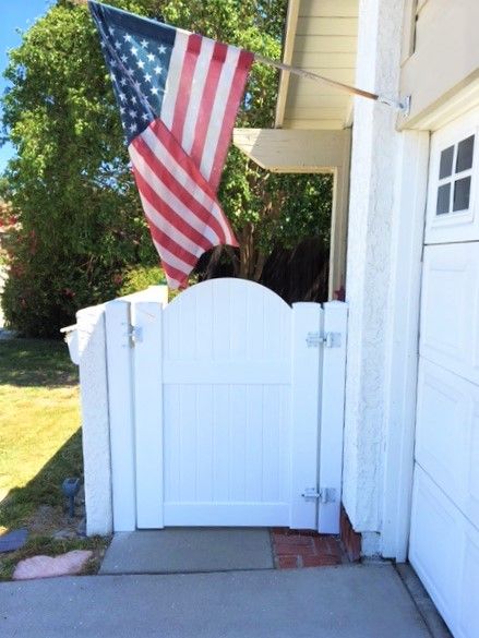 An american flag is flying over a white gate