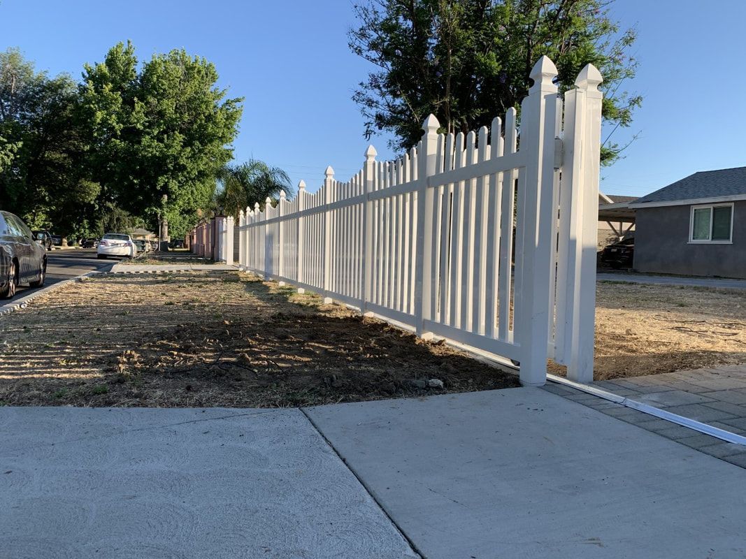 A white picket fence along a sidewalk in front of a house.