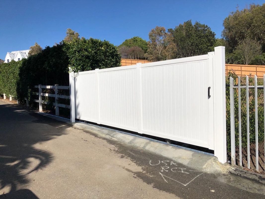 A white fence is sitting on the side of a road.