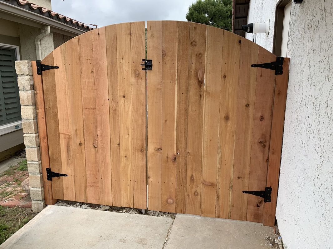 A wooden gate is sitting on a sidewalk in front of a house.