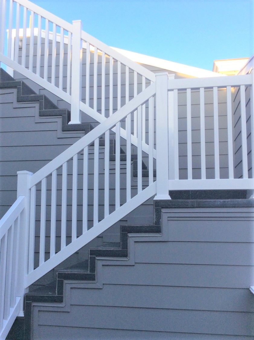 A set of stairs with a white railing and a blue sky in the background