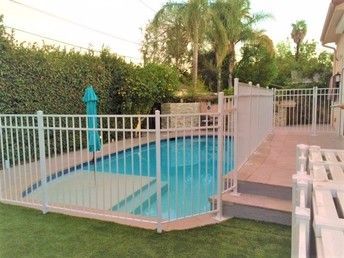 A large swimming pool surrounded by a white fence and stairs.
