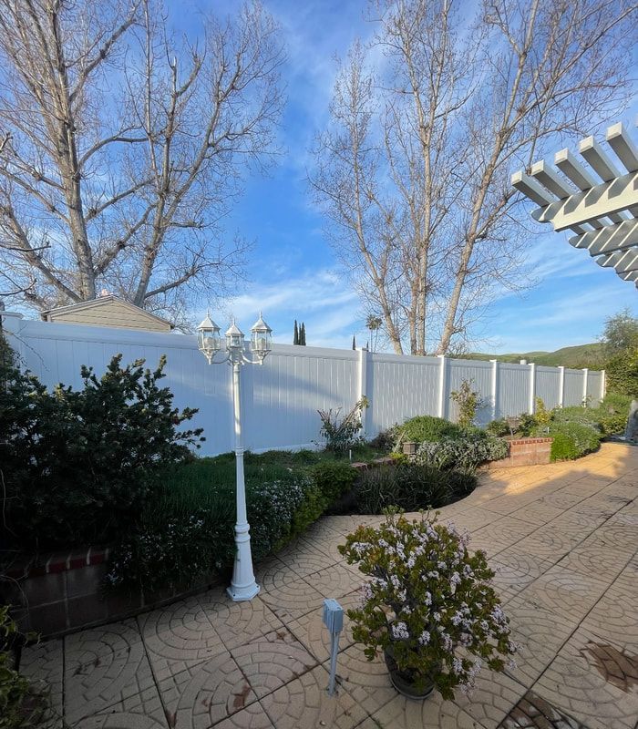 A backyard with a white fence and a pergola