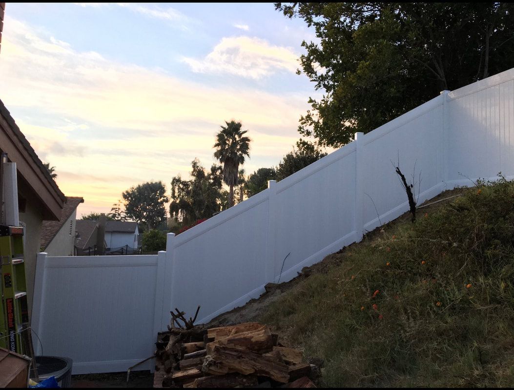A white fence is sitting on top of a grassy hill.
