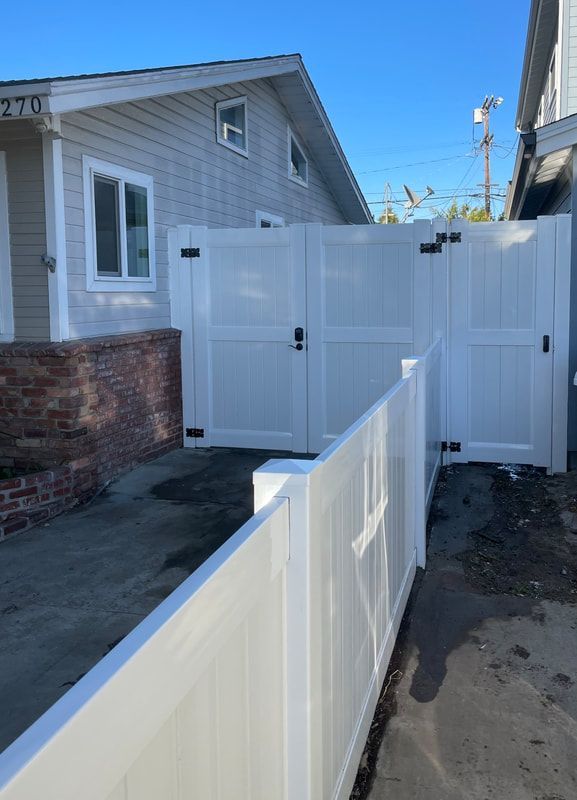 A white fence with a gate in front of a house.