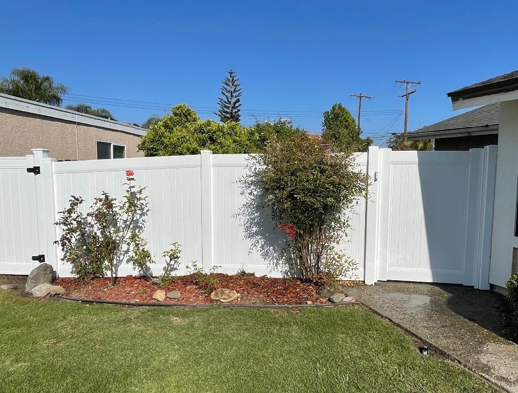 There is a white fence in the backyard of a house.