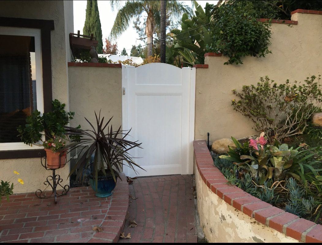 A white gate is in the middle of a brick walkway