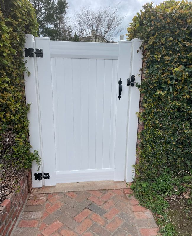 A white gate is sitting on a brick walkway next to a brick wall.