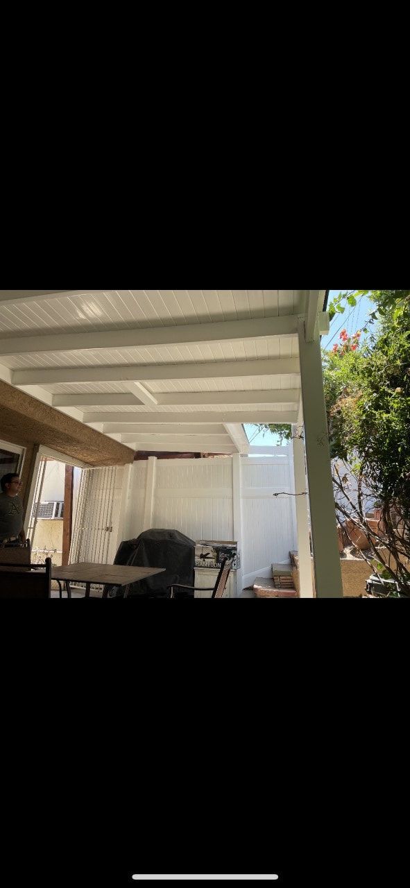 A patio with a white roof and a table and chairs underneath it.