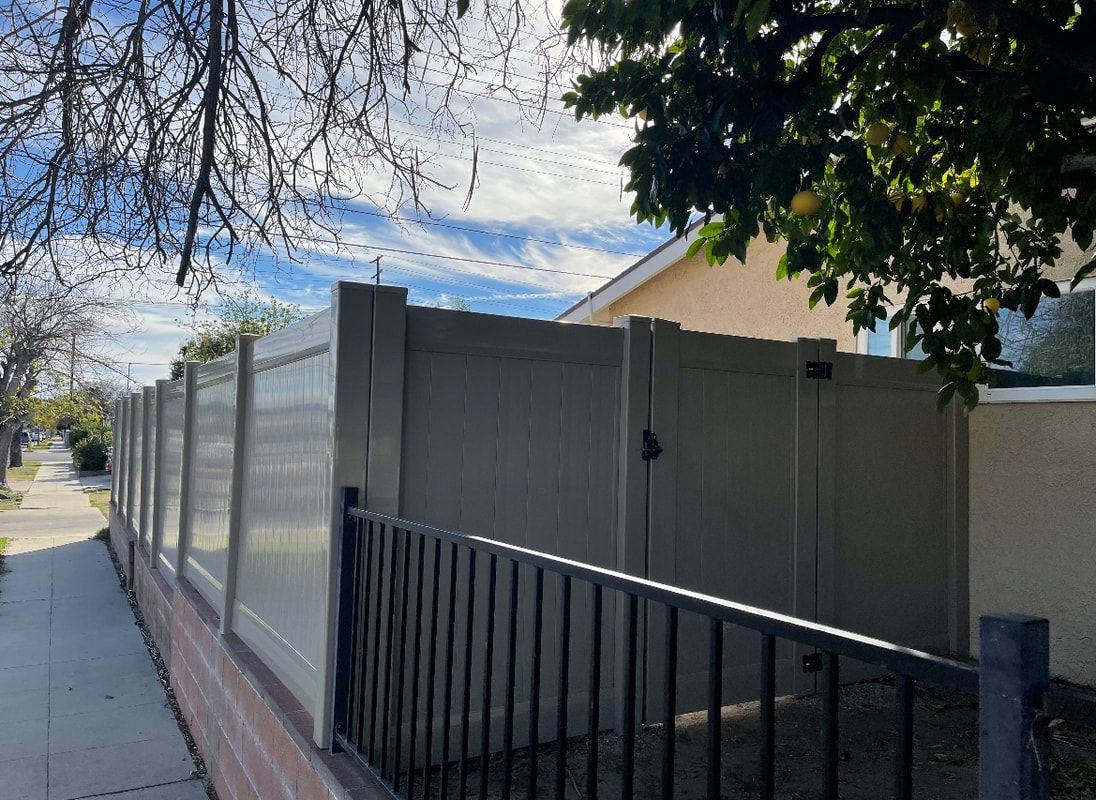 A white fence is sitting next to a house on a sidewalk.