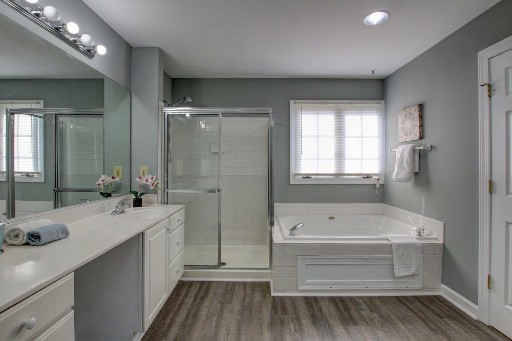 A bathroom with a tub , shower , sink and mirror.