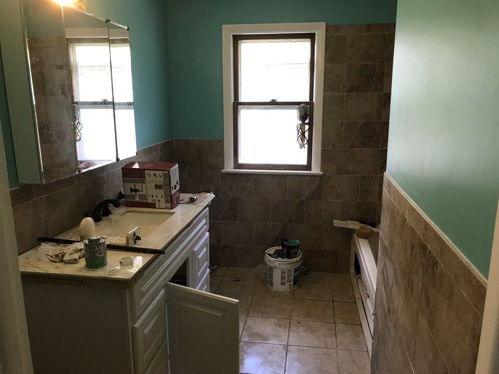 A bathroom with a sink , mirror and window.