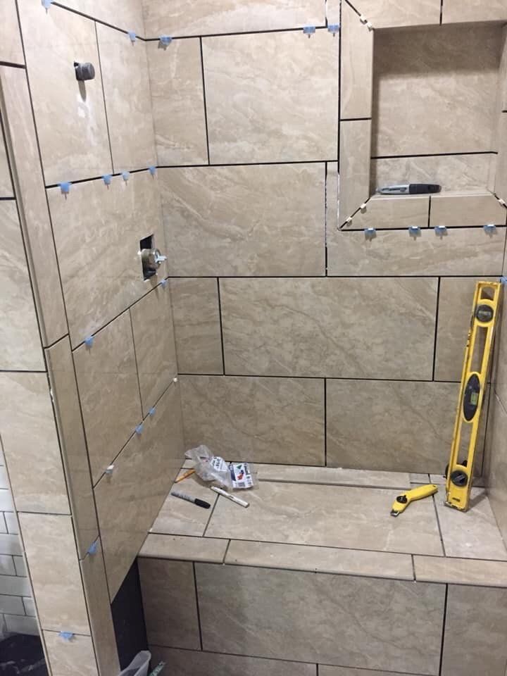 A bathroom with tile walls and a yellow level on the floor.