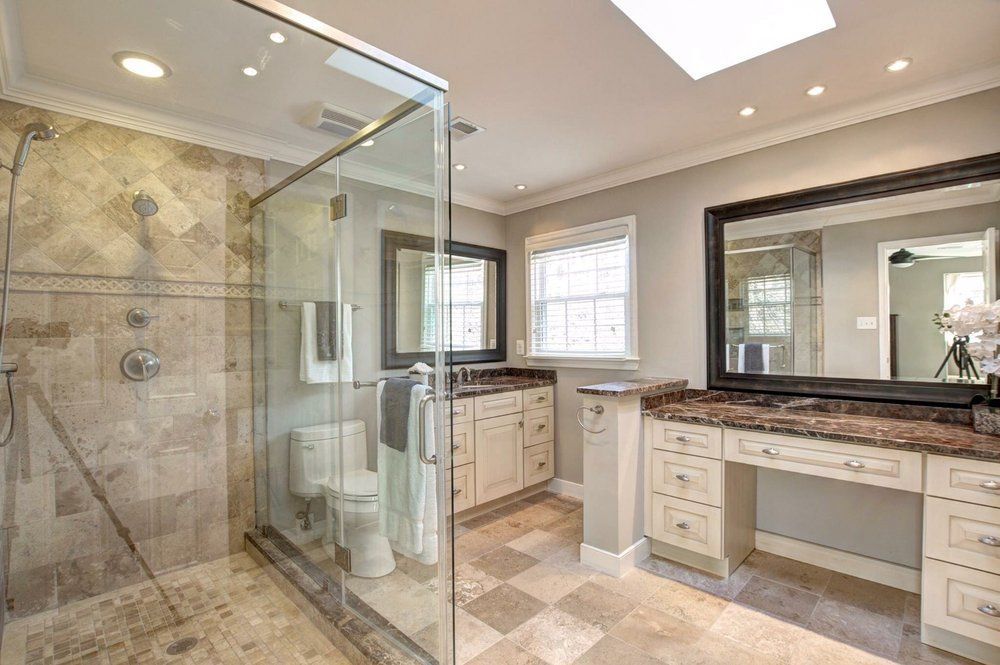 A bathroom with a walk in shower , toilet , sink and mirror.