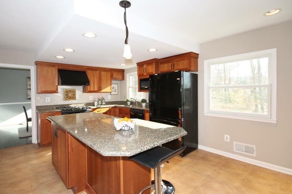 A kitchen with a large island and a black refrigerator