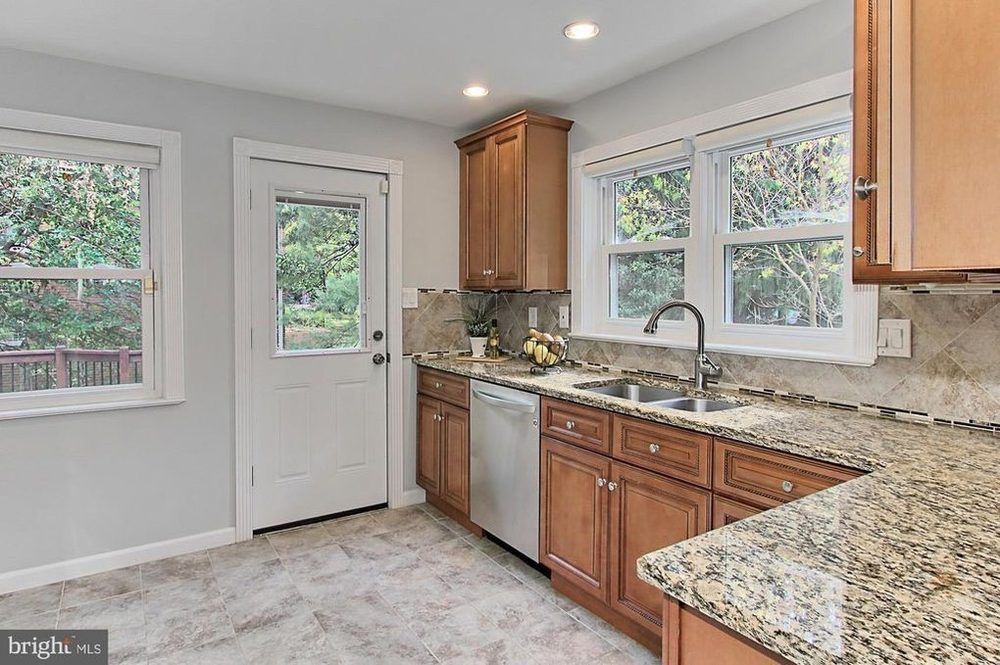 A kitchen with granite counter tops , wooden cabinets , a sink , and a dishwasher.