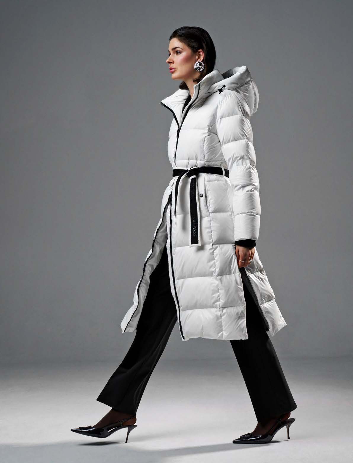 Eine Frau in weißer Daunenjacke, schwarzer Hose und High Heels geht und blickt weg. Grauer Hintergrund.