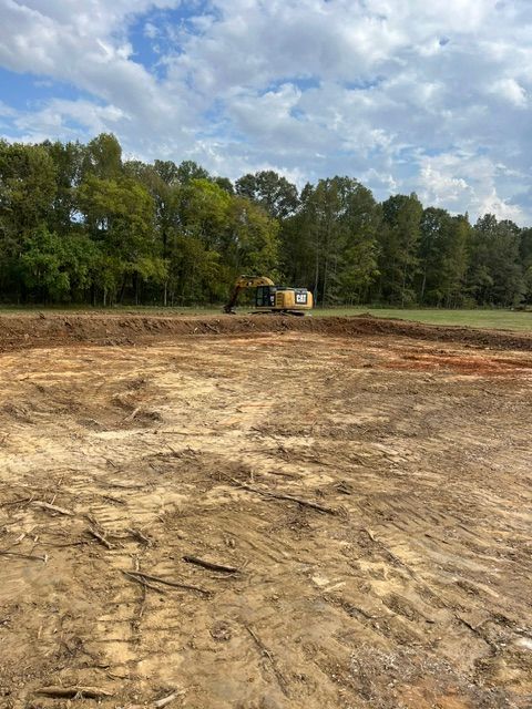 A large dirt field with trees in the background.