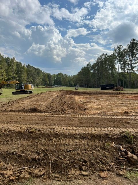 A construction site with a lot of dirt and trees in the background.