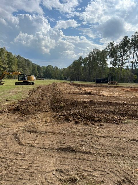 A construction site with a lot of dirt and trees in the background.