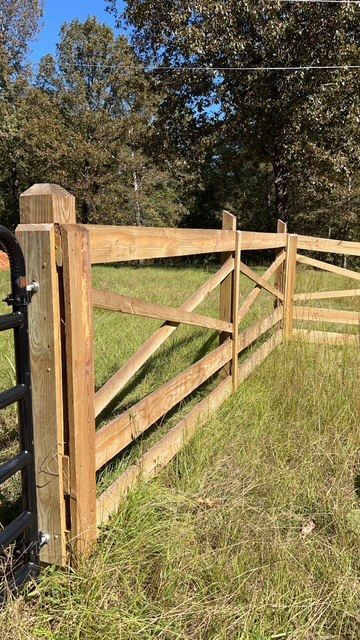 A wooden fence is sitting in the middle of a grassy field.