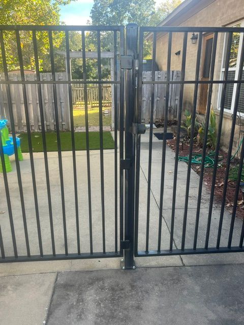 A black metal gate is open to a backyard