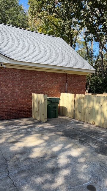 A brick house with a white roof and a wooden fence in front of it.