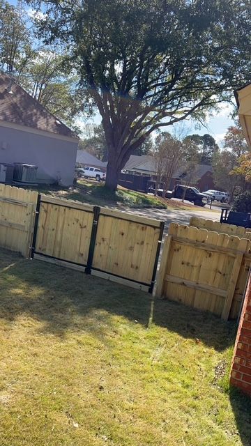 A wooden fence in a backyard with a tree in the background.