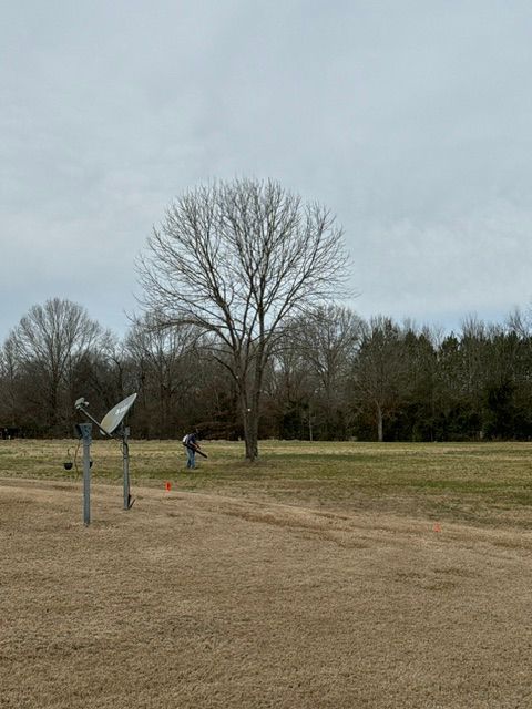 A satellite dish is sitting in the middle of a field.
