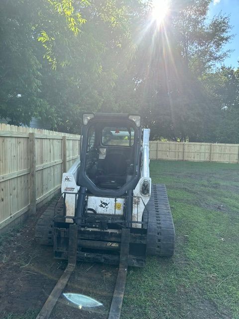 A bobcat is parked in a backyard next to a wooden fence.
