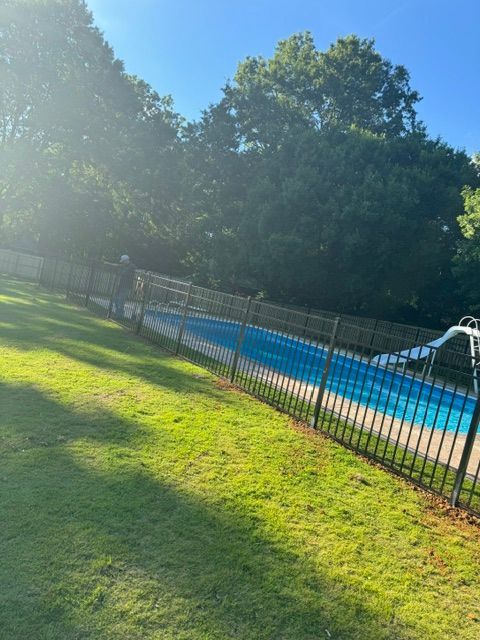 A large swimming pool surrounded by a fence and trees.