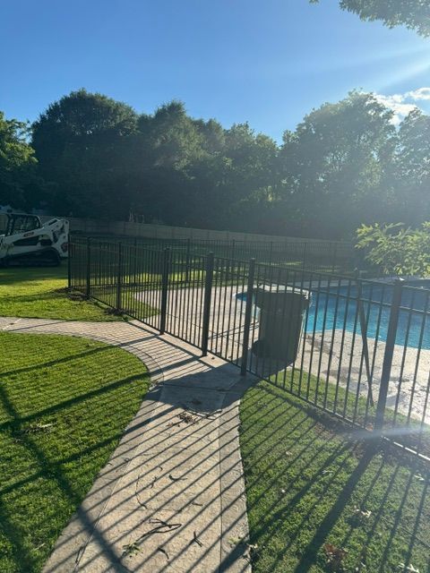 A wrought iron fence surrounds a swimming pool in a backyard.