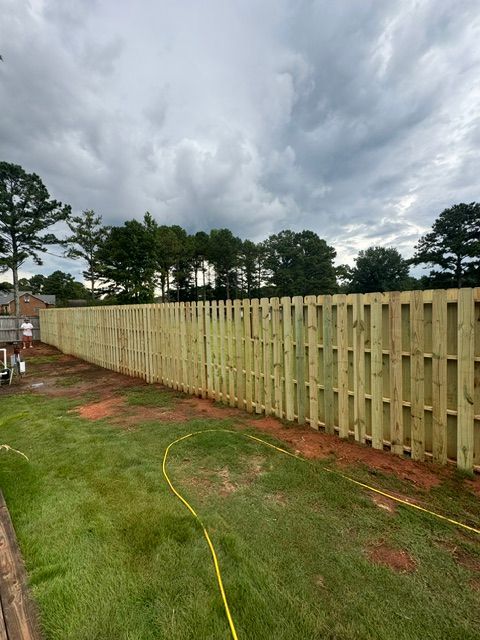 A wooden fence is being built in a backyard.