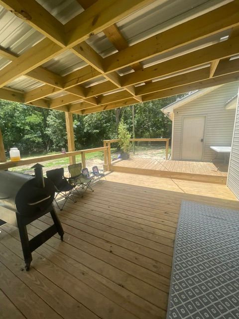 A wooden deck with a metal roof and a grill on it