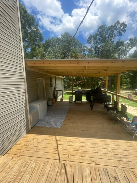 A wooden deck with a swing and a grill underneath it.