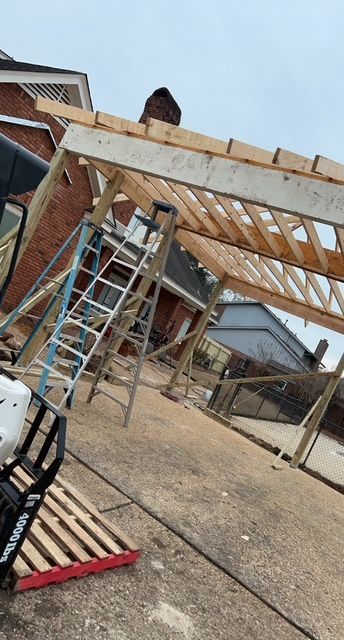 A wooden structure is being built in front of a brick house.